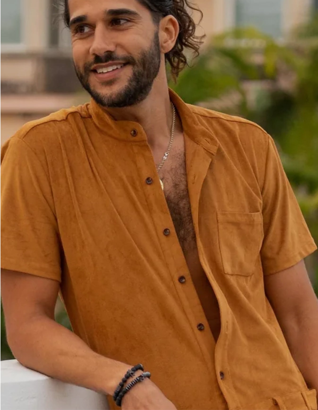 Man wearing a mustard yellow shirt with a blurred outdoor background