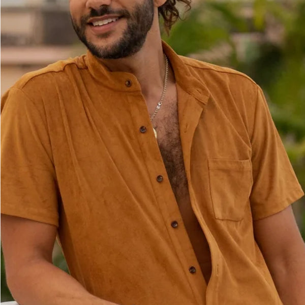 Man wearing a mustard yellow shirt with a blurred outdoor background