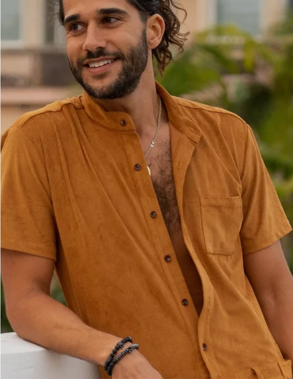 Man wearing a mustard yellow shirt with a blurred outdoor background